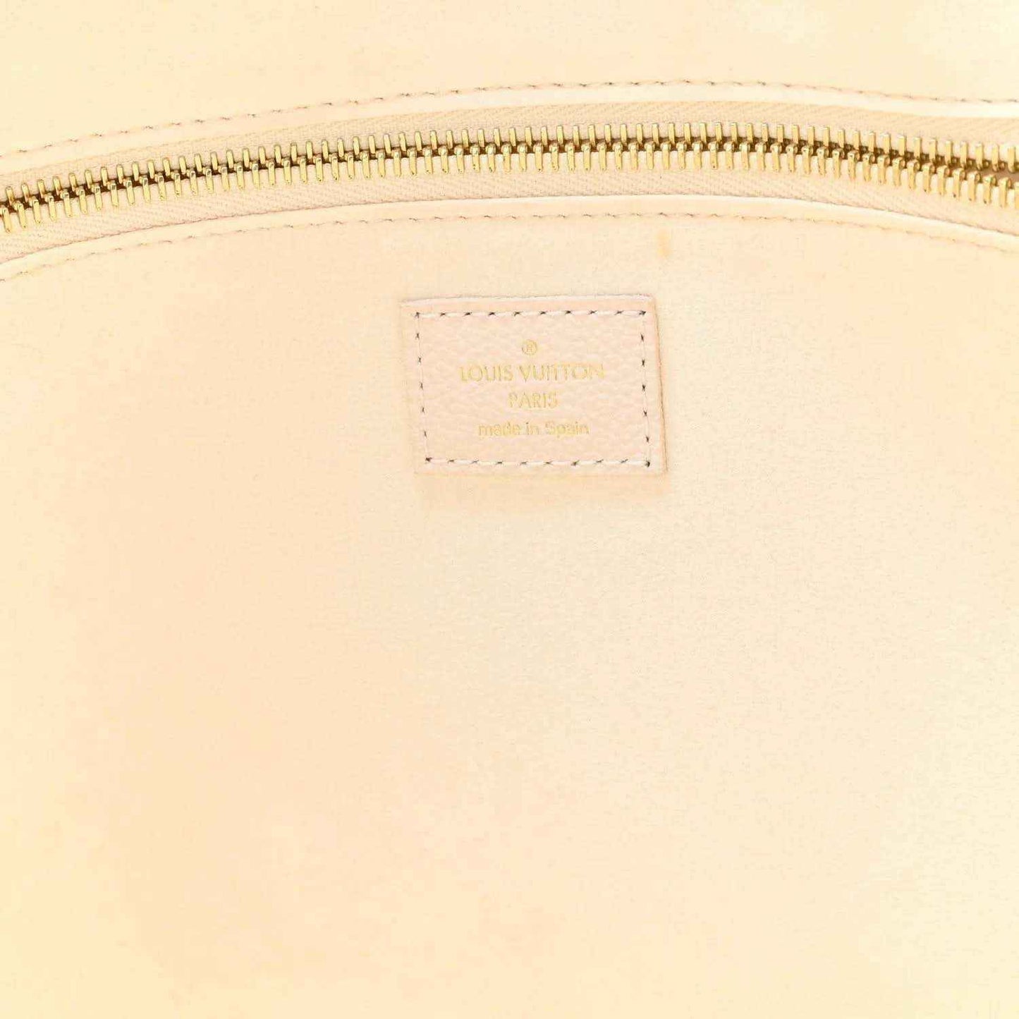 Neutral leather tote close-up of rectangular brand label near zipper