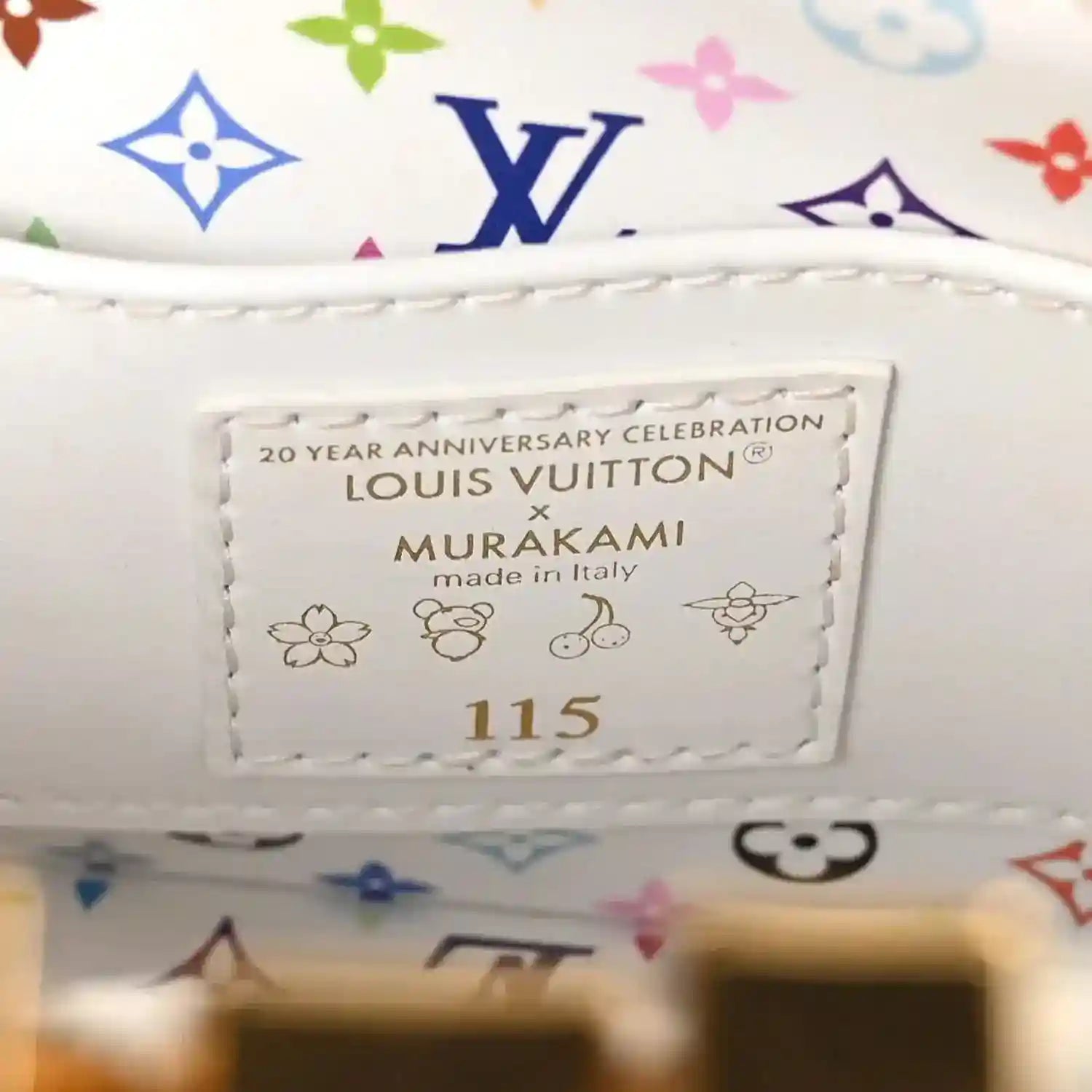 White leather luggage tag with text and multicolor monogram trim on the handbag