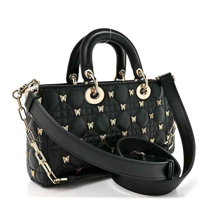 Black quilted top handle bag with butterfly charms and wide shoulder strap, front angle