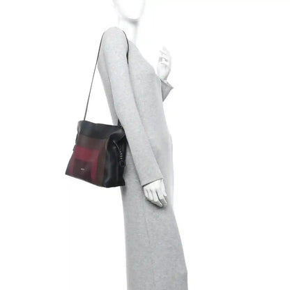 Burgundy-and-black Flamenco knot clutch worn crossbody with black strap