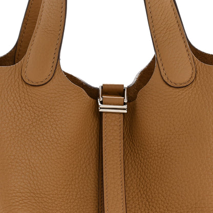 Tan leather bucket bag with silver-tone strap clasp and handles
