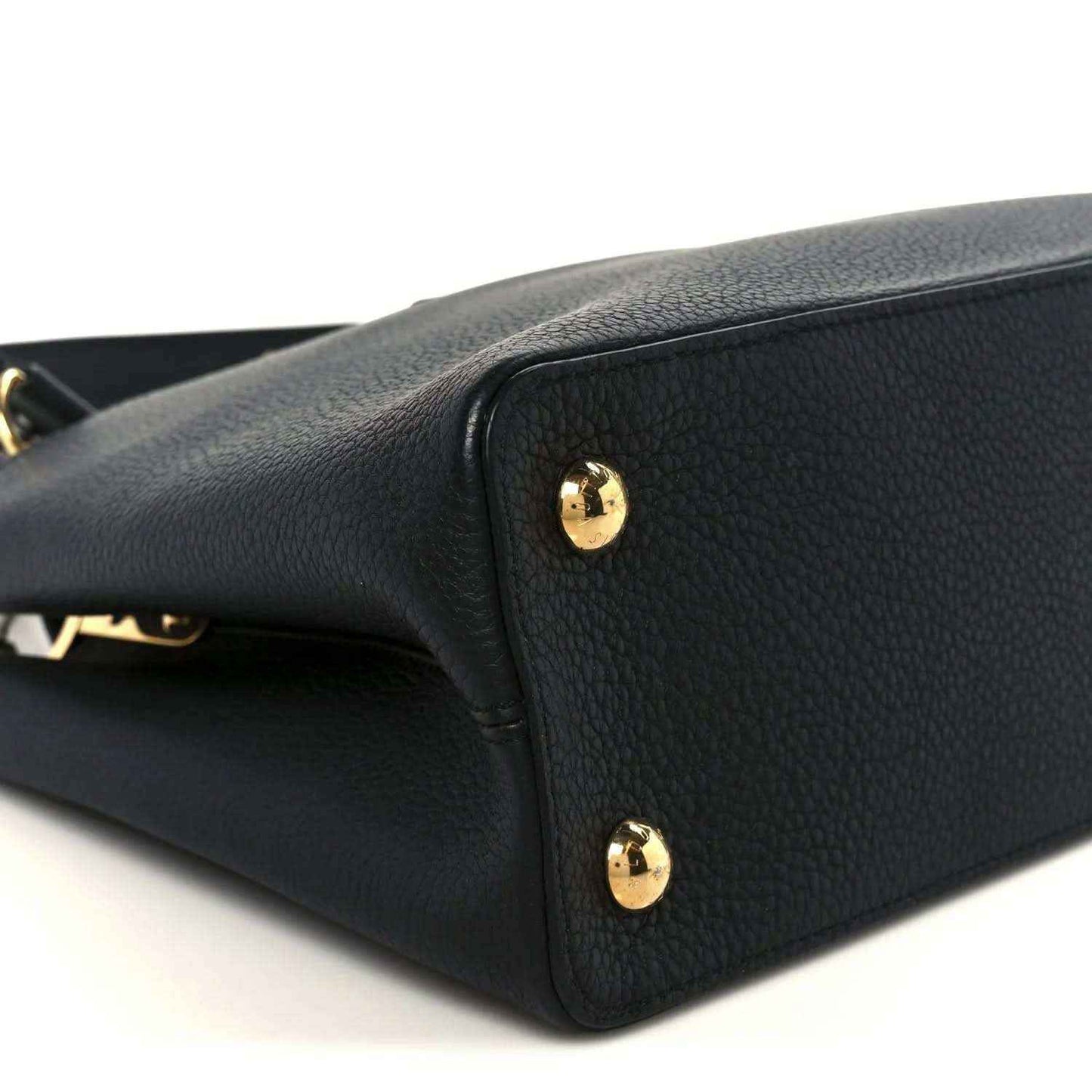 Black leather handbag close-up with gold stud accents on side panel