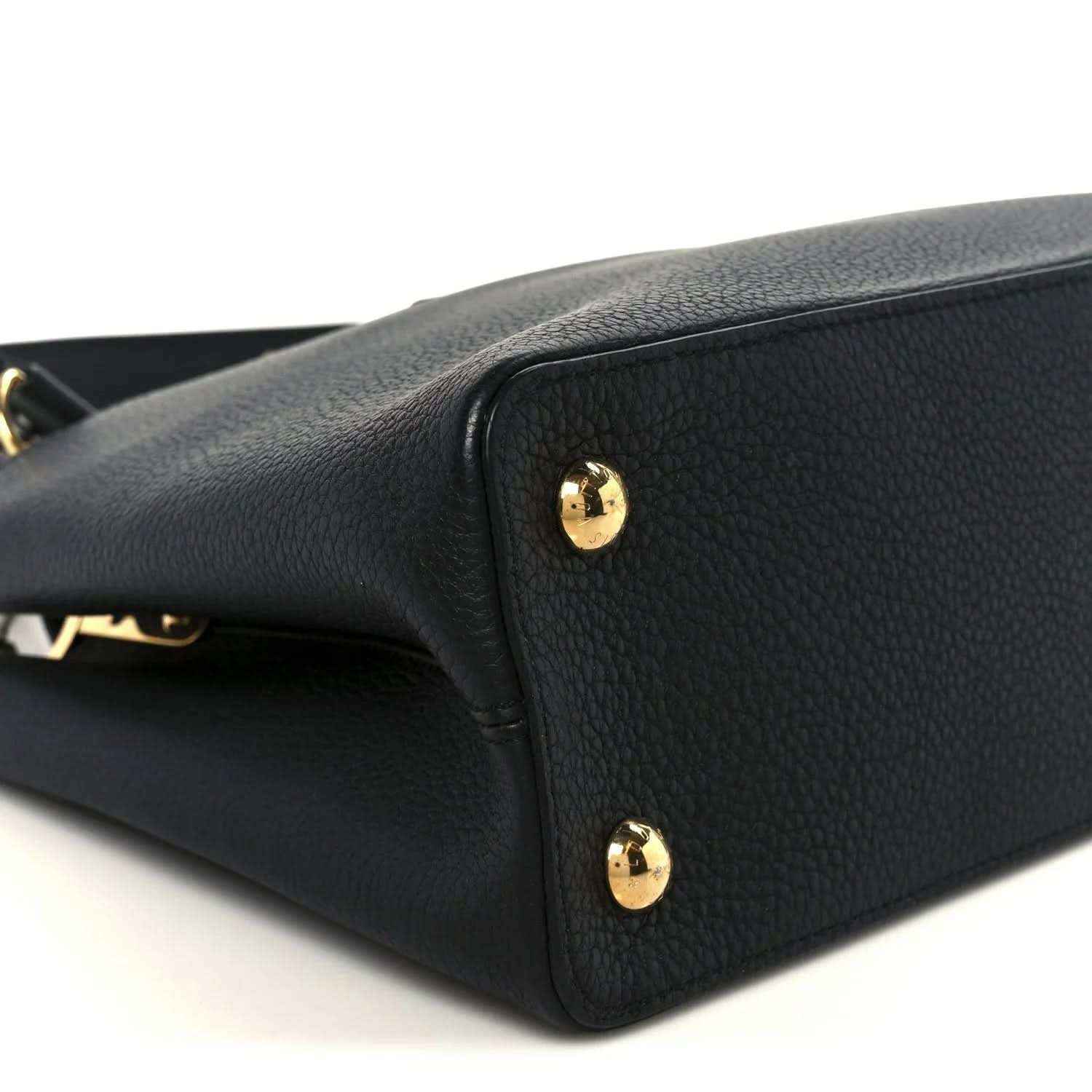 Black leather handbag close-up with gold stud accents on side panel