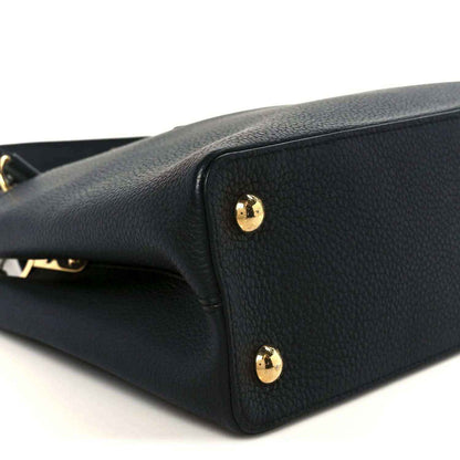 Black leather handbag close-up with gold stud accents on side panel
