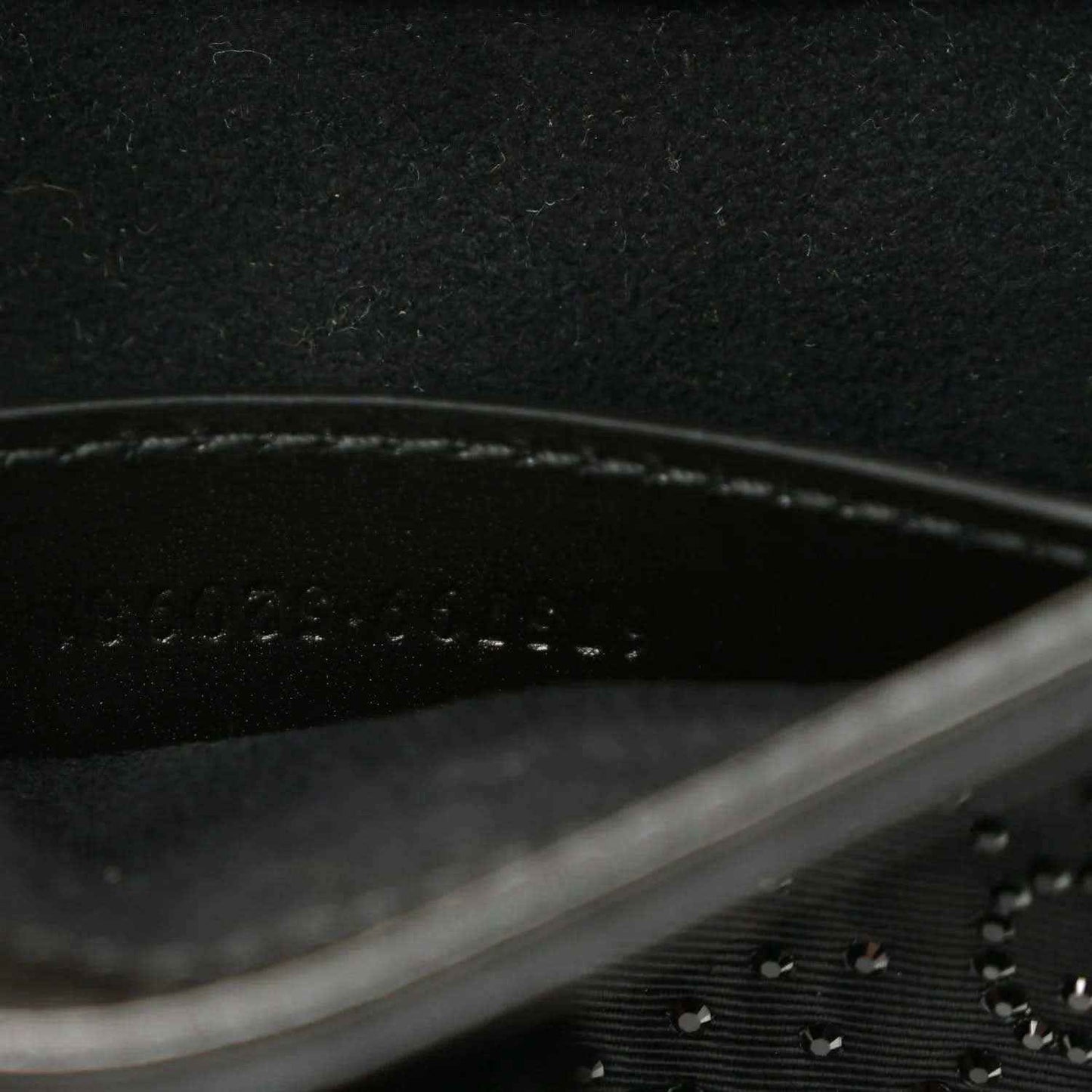 Close-up of black hobo bag seam line and embossed monogram-style texture.