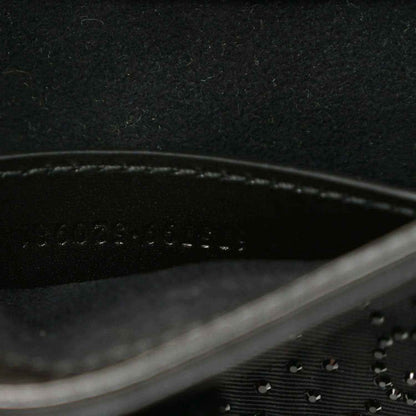 Close-up of black hobo bag seam line and embossed monogram-style texture.
