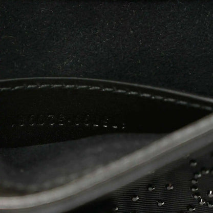 Close-up of black hobo bag seam line and embossed monogram-style texture.
