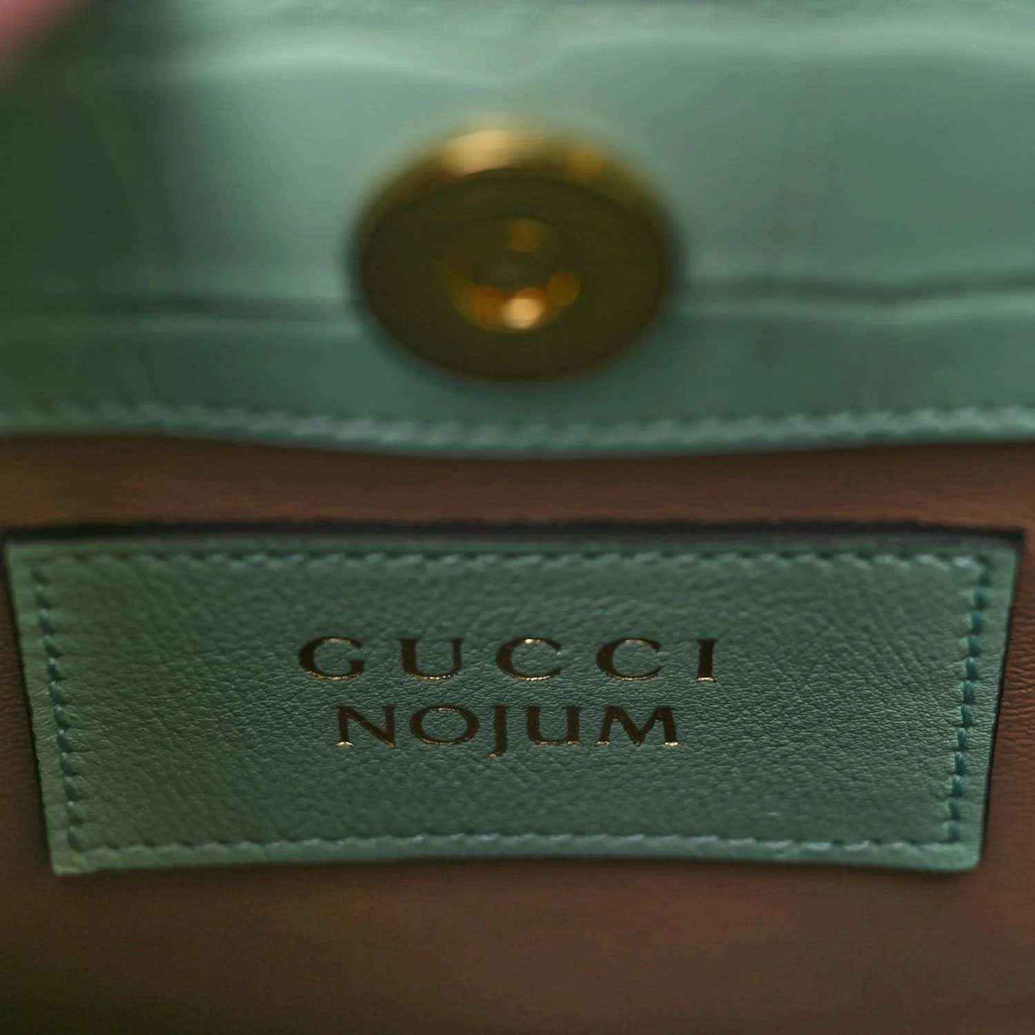 Gucci label on green tote bag lining with gold-tone rivet and stitched border