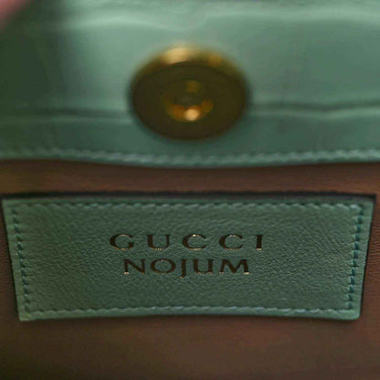 Gucci label on green tote bag lining with gold-tone rivet and stitched border