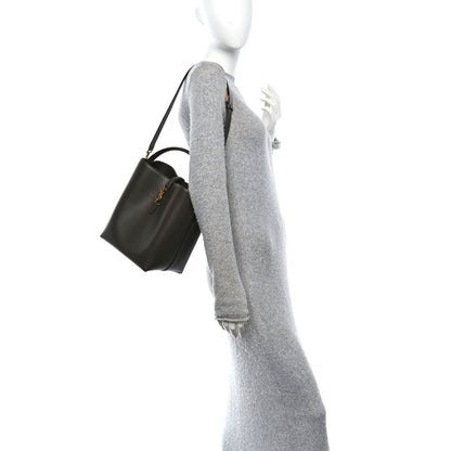 Saint Laurent bucket bag worn crossbody with adjustable strap, deep musk leather.