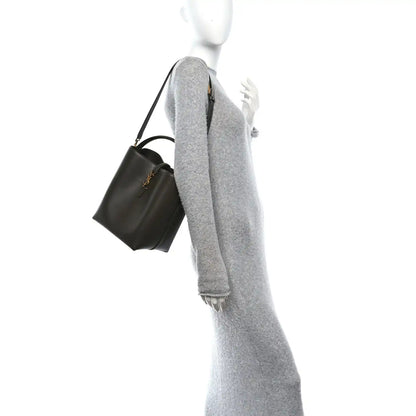 Saint Laurent bucket bag worn crossbody with adjustable strap, deep musk leather.