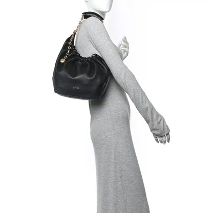 Loewe small squeeze bag in dark nappa leather with gold chain strap, held on wrist