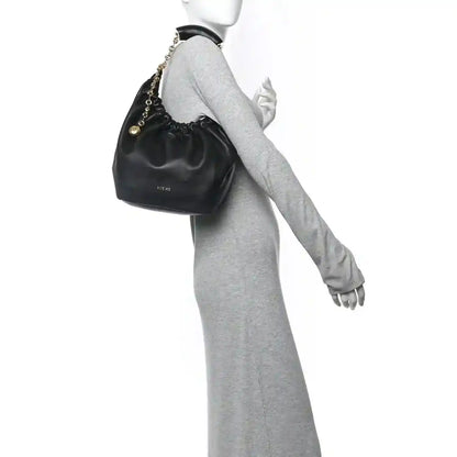 Loewe small squeeze bag in dark nappa leather with gold chain strap, held on wrist
