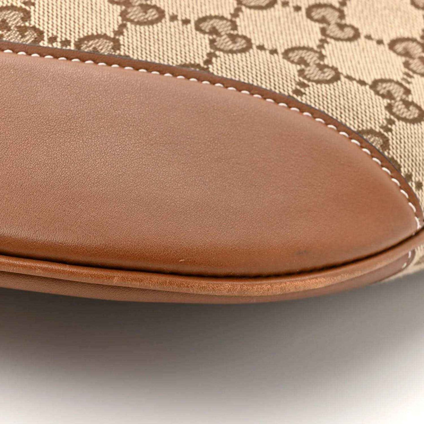 Large shoulder bag curved leather trim with visible stitching over monogram canvas