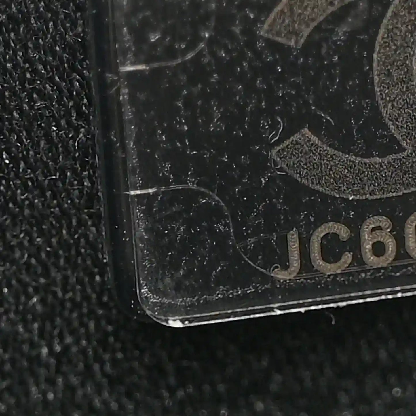 Black caviar-textured leather corner detail with partial logo patch.