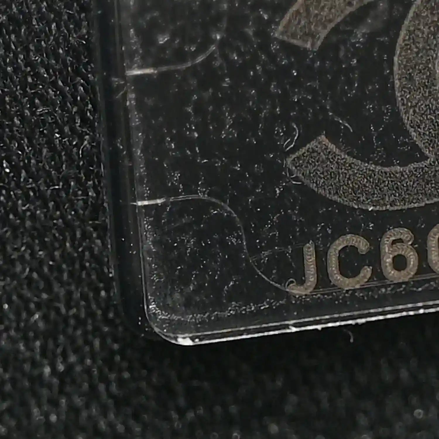 Black caviar-textured leather corner detail with partial logo patch.