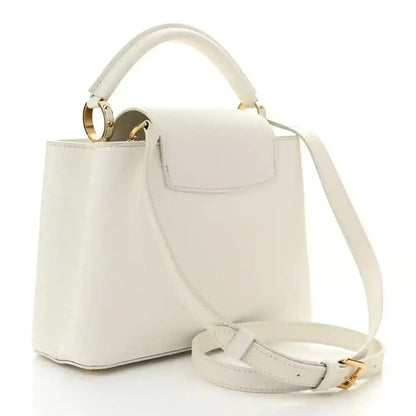 White structured top-handle bag with flap, crossbody strap, and gold hardware