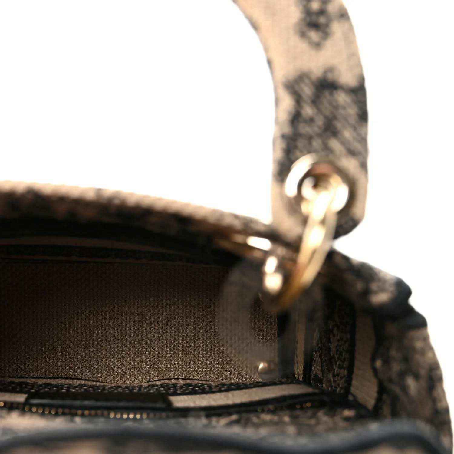 Gold-tone D-ring and woven strap on a black-and-cream embroidered mini handbag