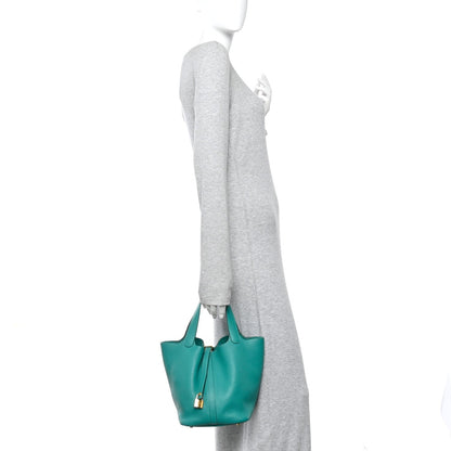 Green leather tote worn at side with top handles and gold-tone lock hardware