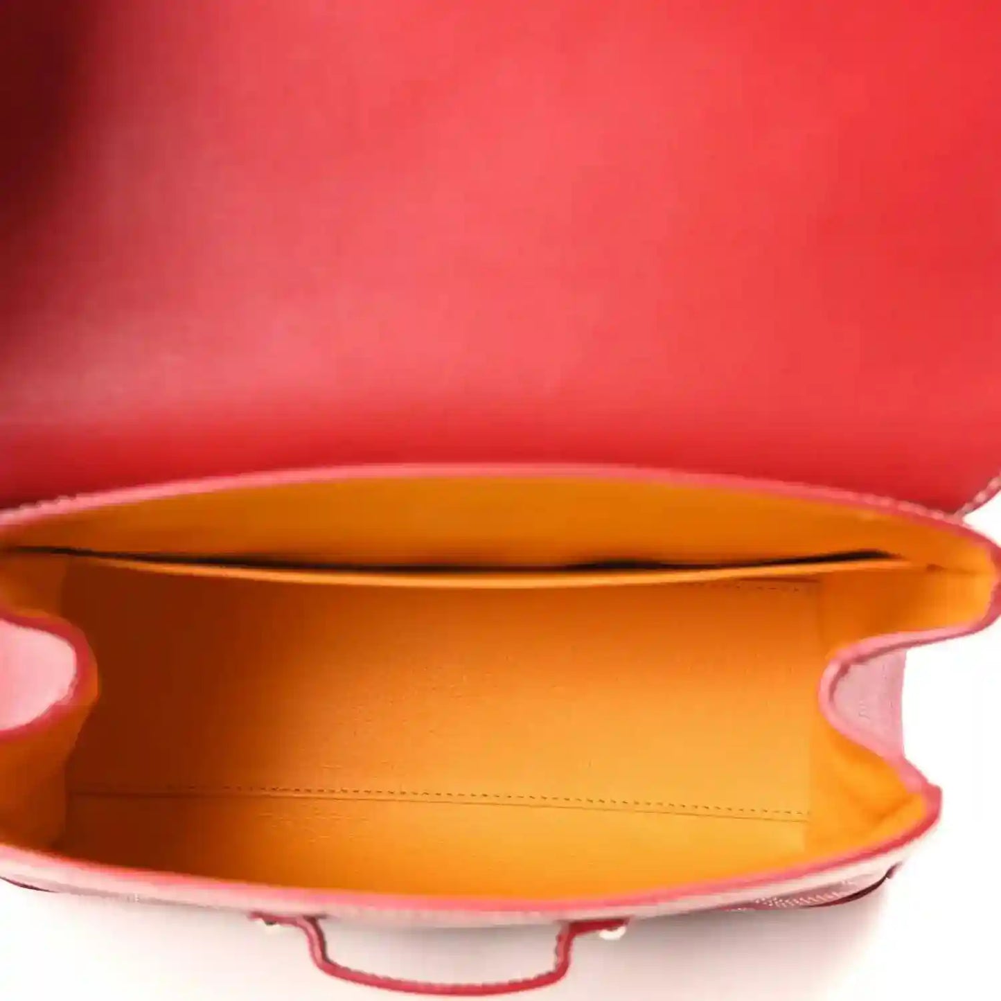 Red mini handbag open top revealing orange fabric lining and leather edge.