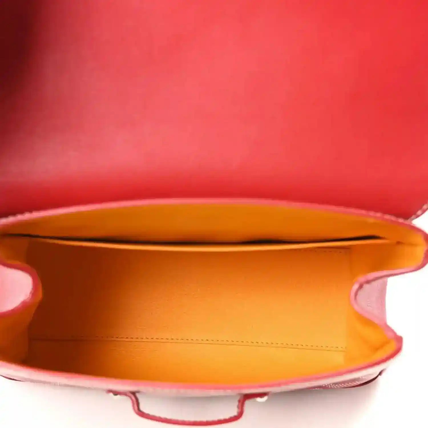 Red mini handbag open top revealing orange fabric lining and leather edge.