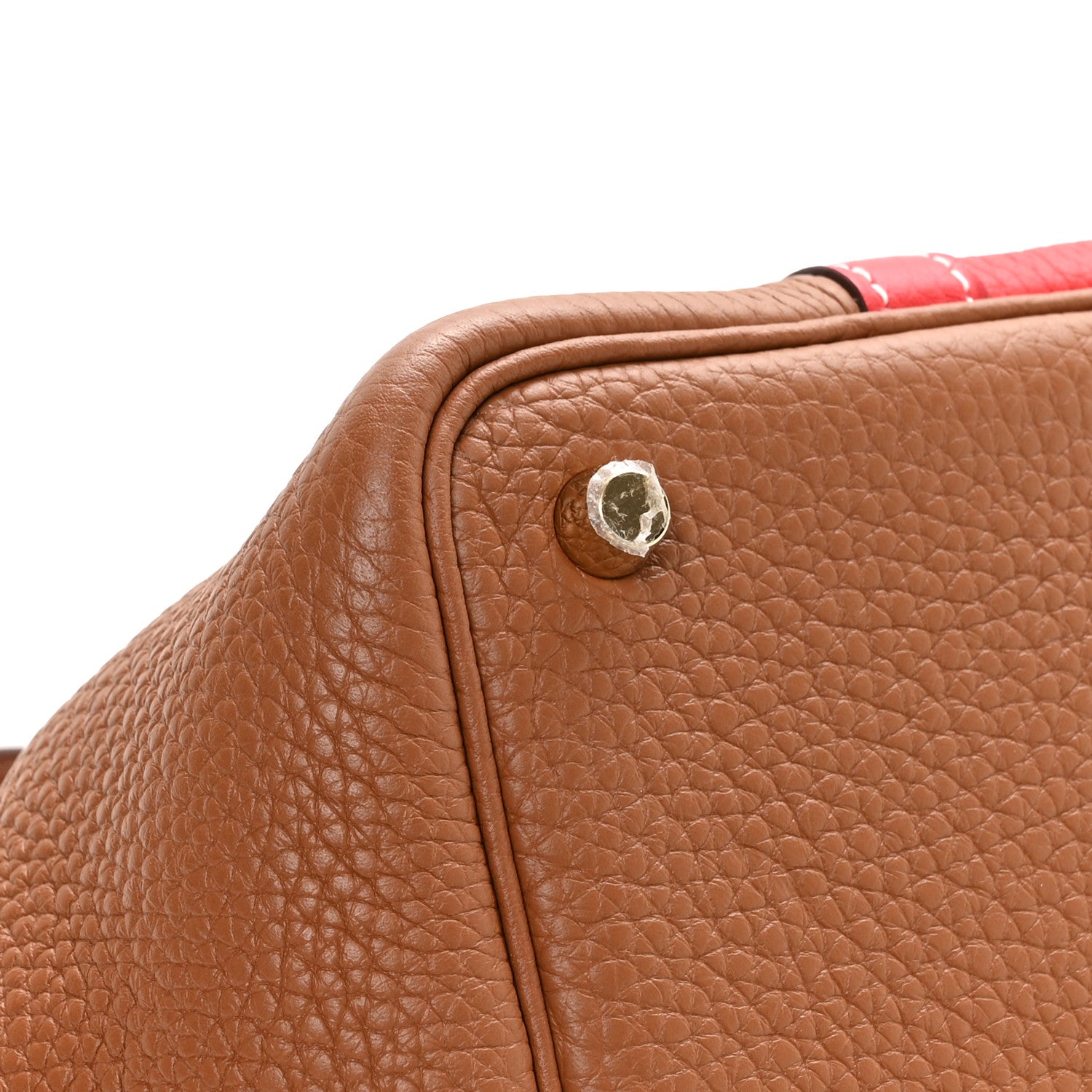 Brown leather corner tab with round metal snap, close-up on two-tone bag