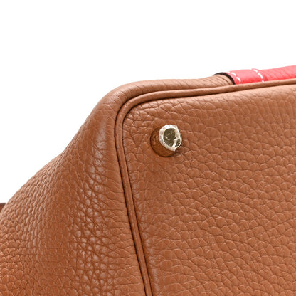 Brown leather corner tab with round metal snap, close-up on two-tone bag