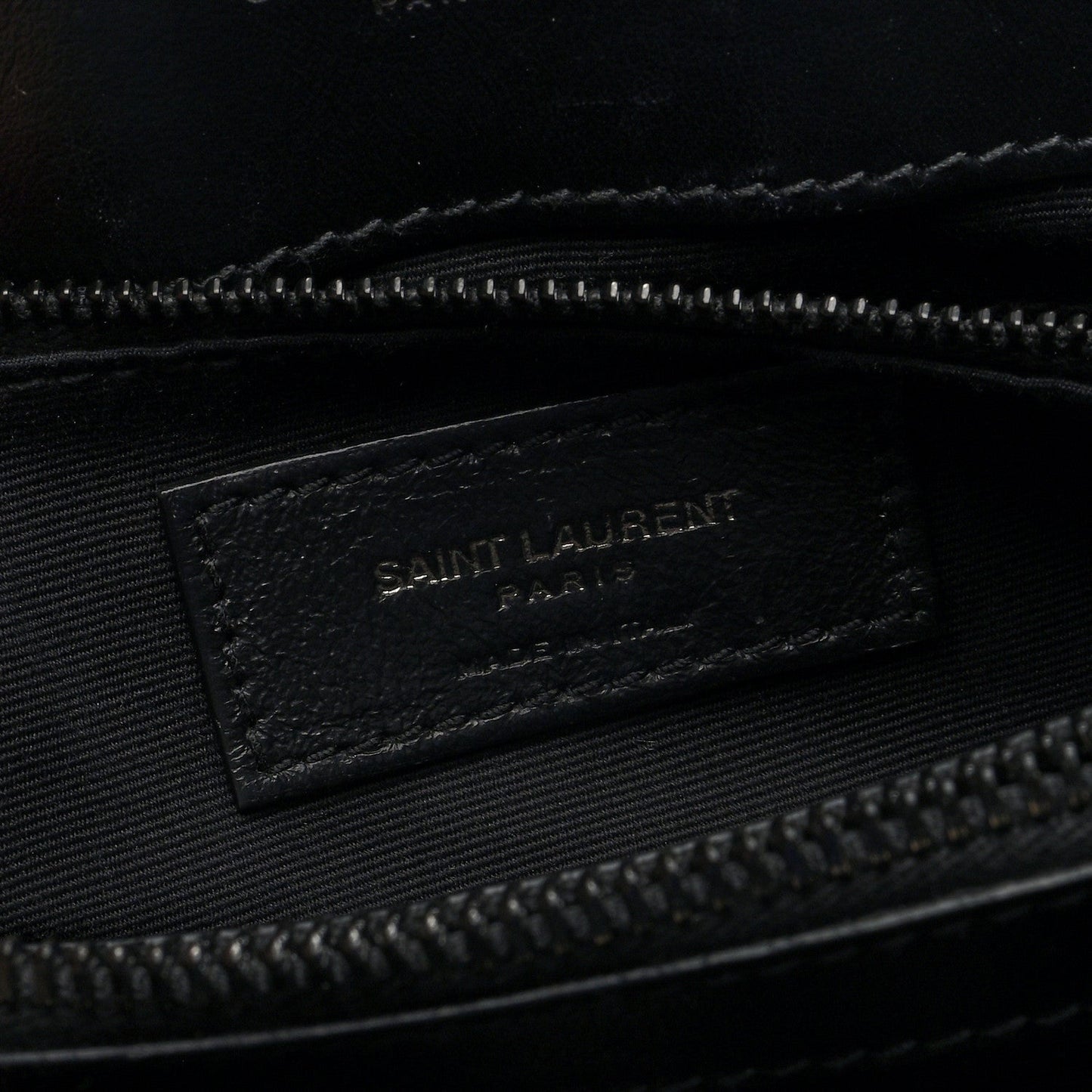 Black fabric interior tag with “SAINT LAURENT” logo inside satchel