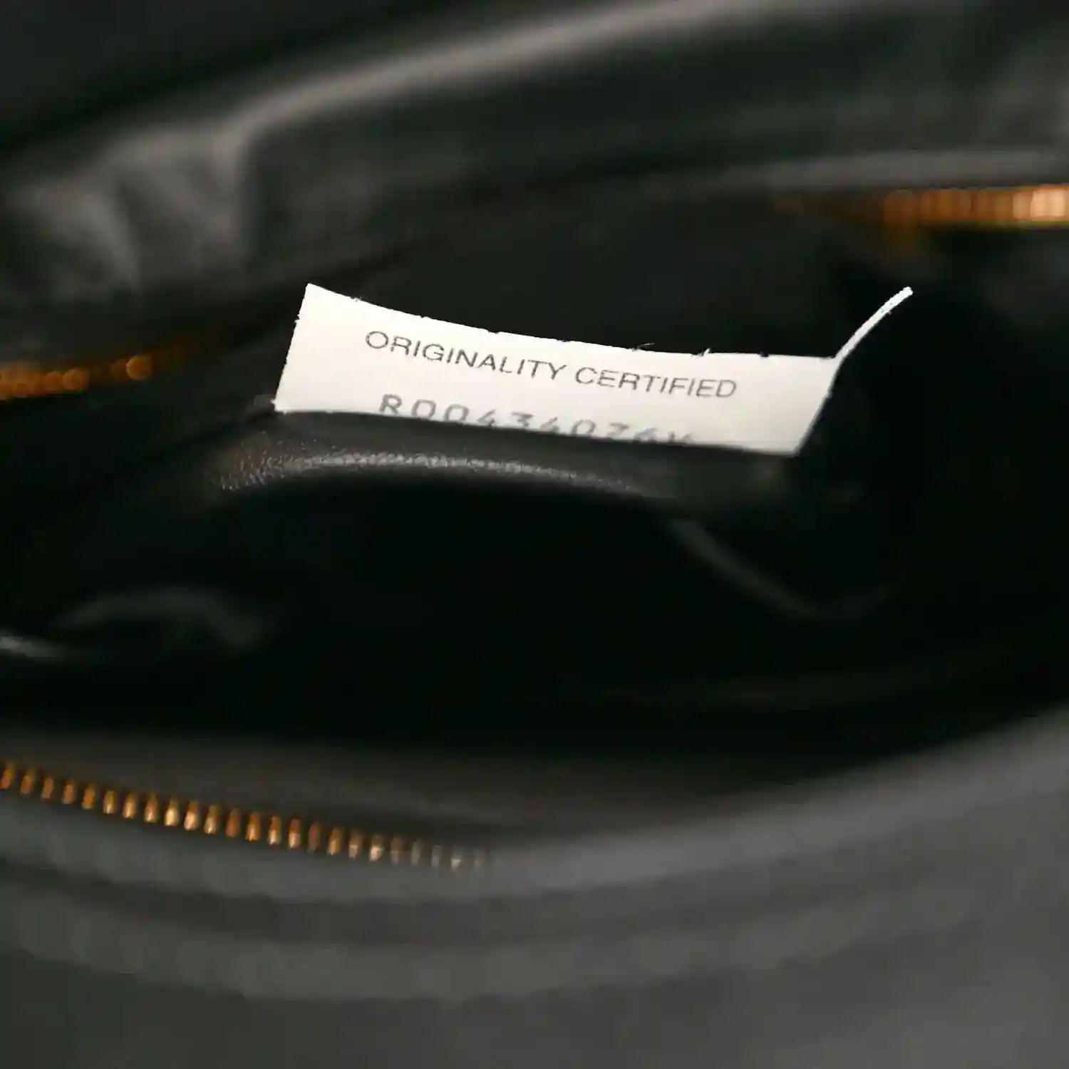 Black leather bag lining with Originality Certified label above gold zipper trim