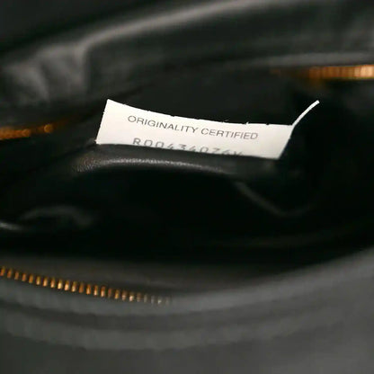 Black leather bag lining with Originality Certified label above gold zipper trim