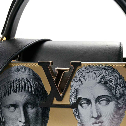 Handbag front close-up with gold LV-style logo, black flap trim, and face-print detail