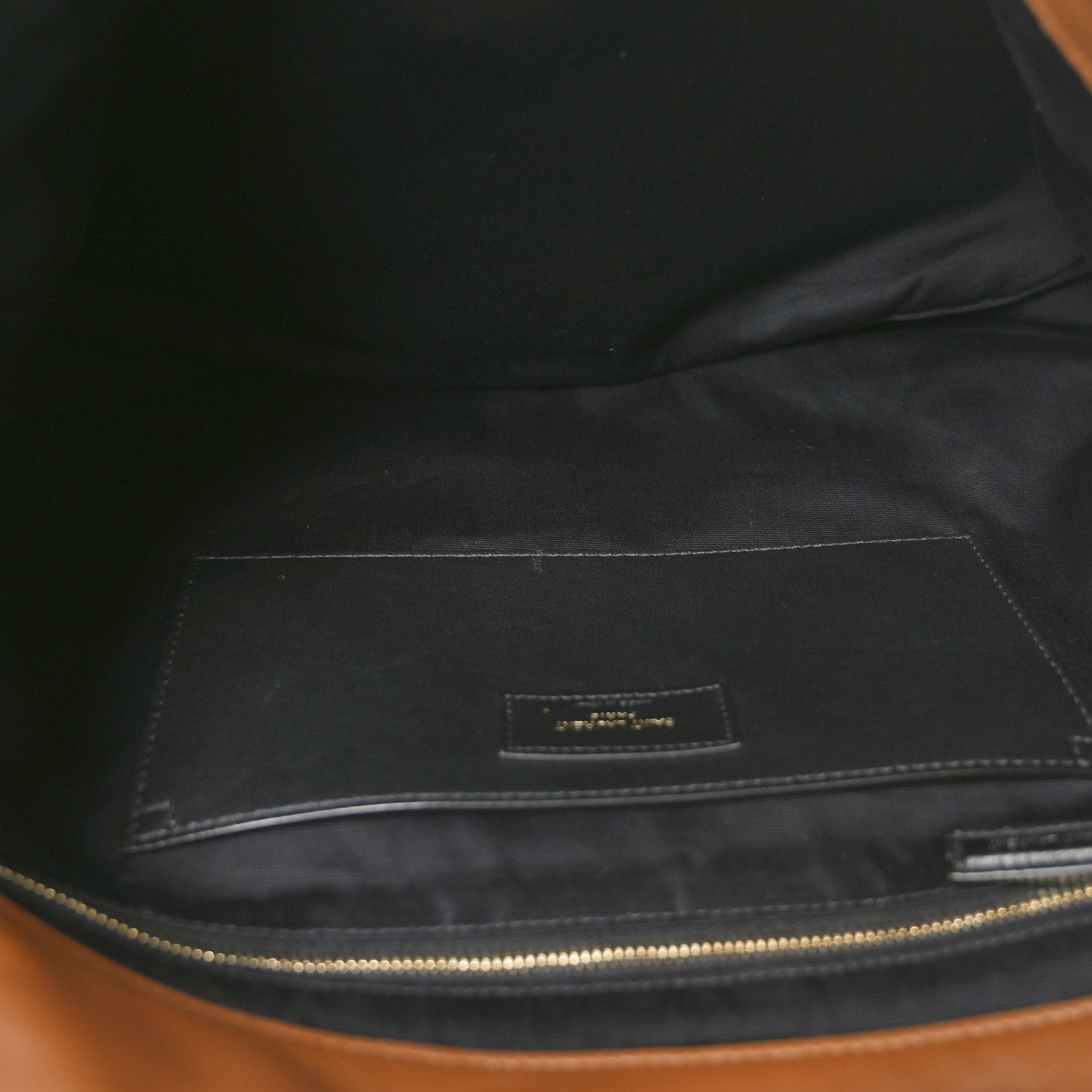 Dark fabric-lined interior of lambskin shoulder bag with zipper and small label