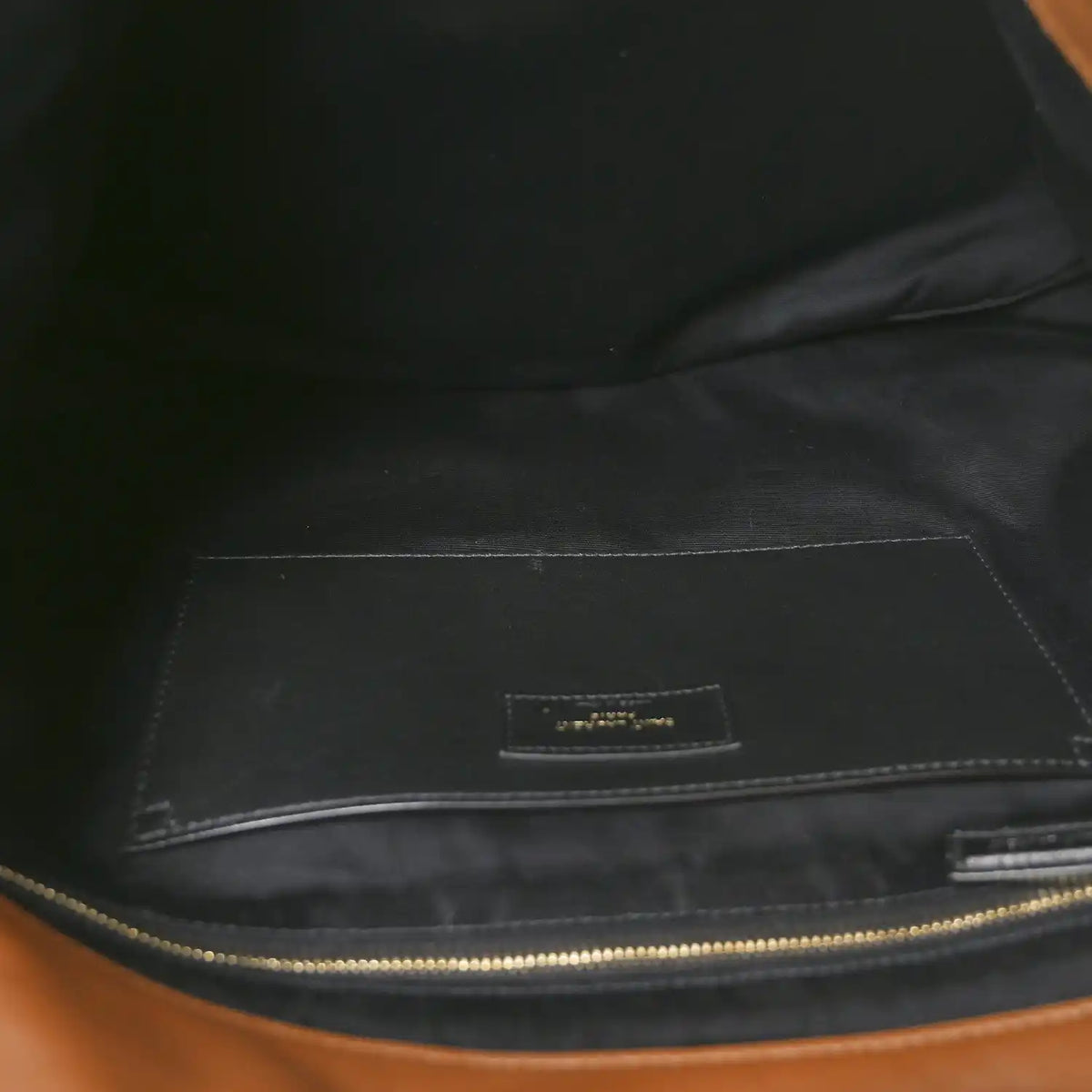 Dark fabric-lined interior of lambskin shoulder bag with zipper and small label