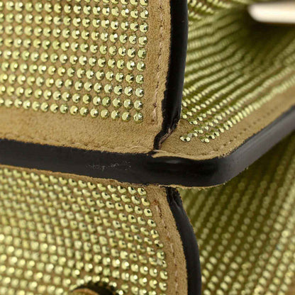 Gold crystal satchel corner detail with black leather edge and embedded studs