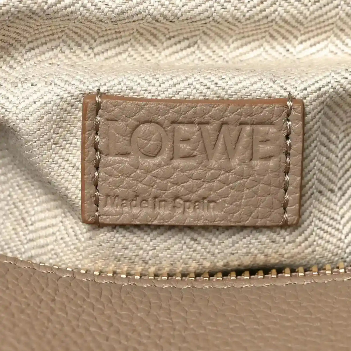 Leather interior label with “LOEWE” text and stitched border on light sand fabric.