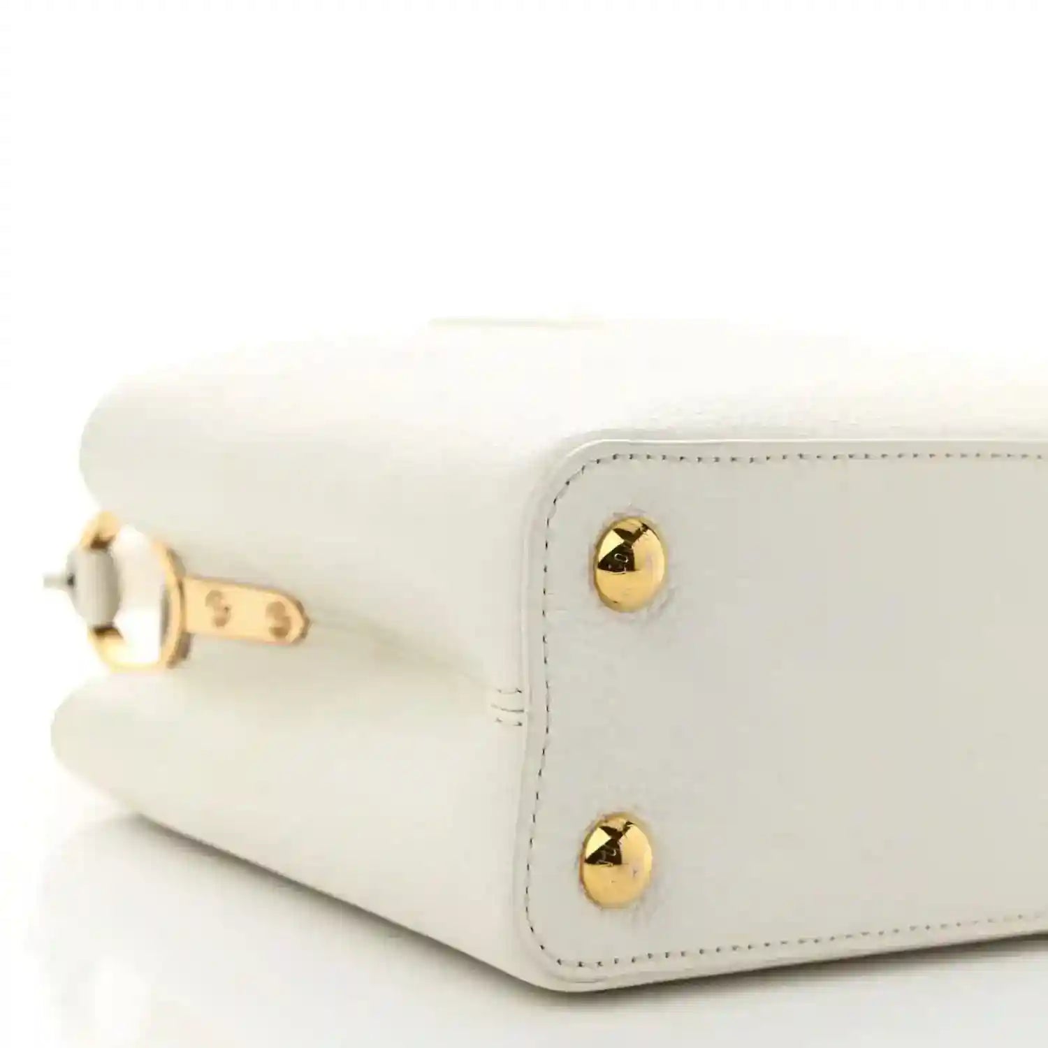 White small top-handle bag side with gold corner studs and rounded flap edge