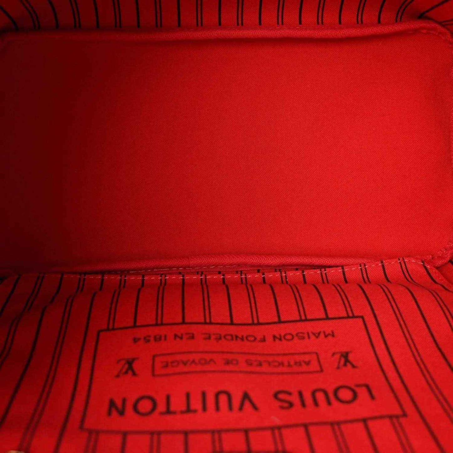 Red fabric interior lining with Louis Vuitton Paris label in tote bag