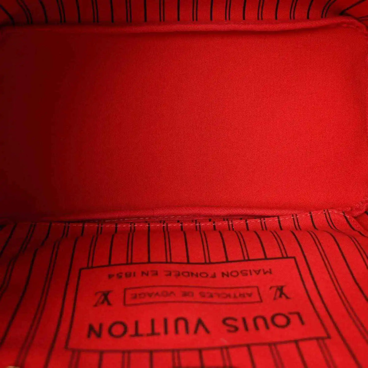 Red fabric interior lining with Louis Vuitton Paris label in tote bag