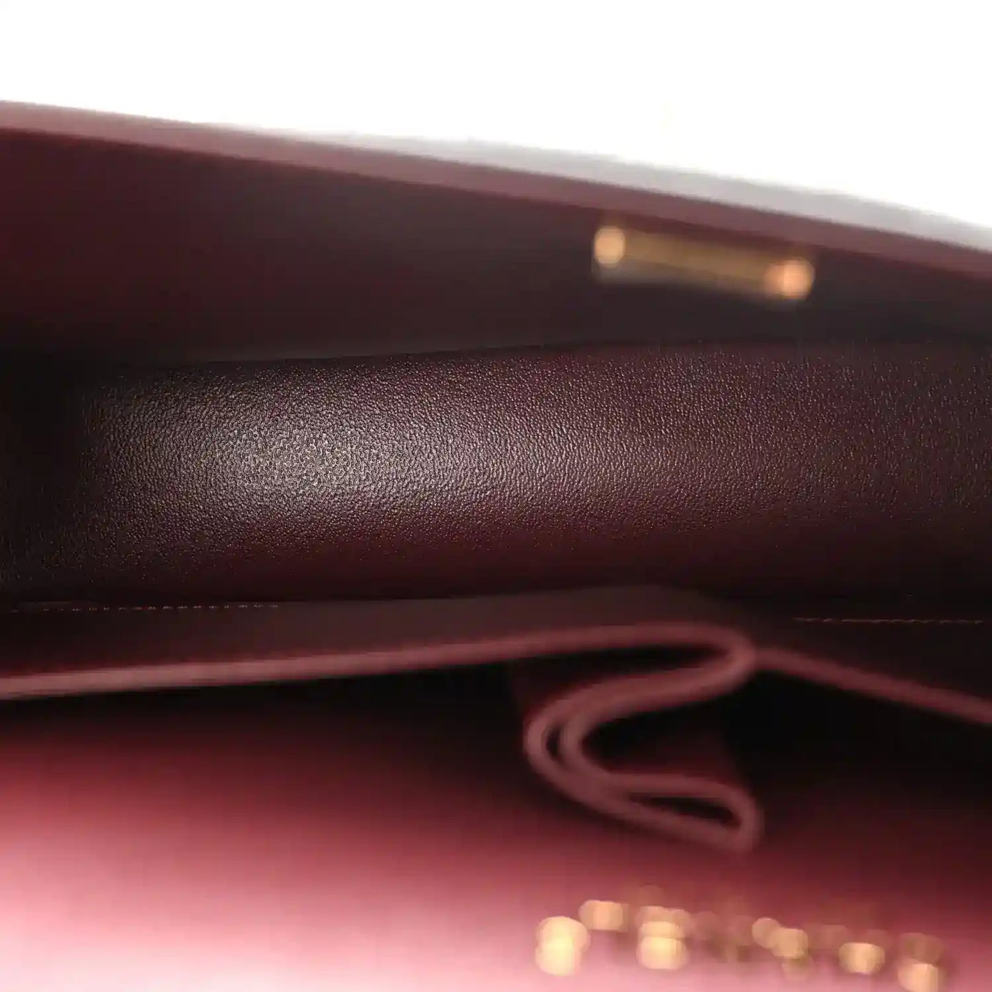 Burgundy fabric lining and inner strap connection inside the black flap bag