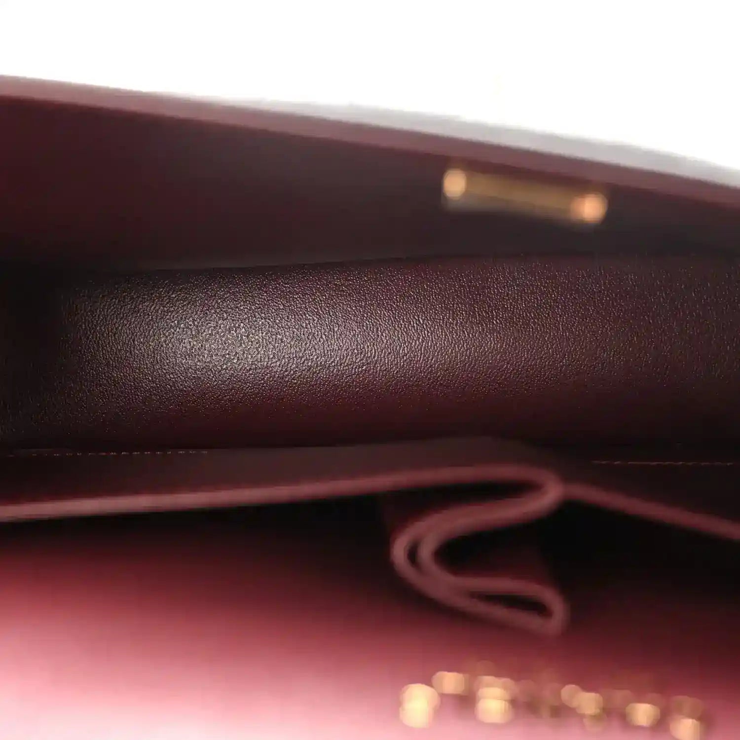 Burgundy fabric lining and inner strap connection inside the black flap bag