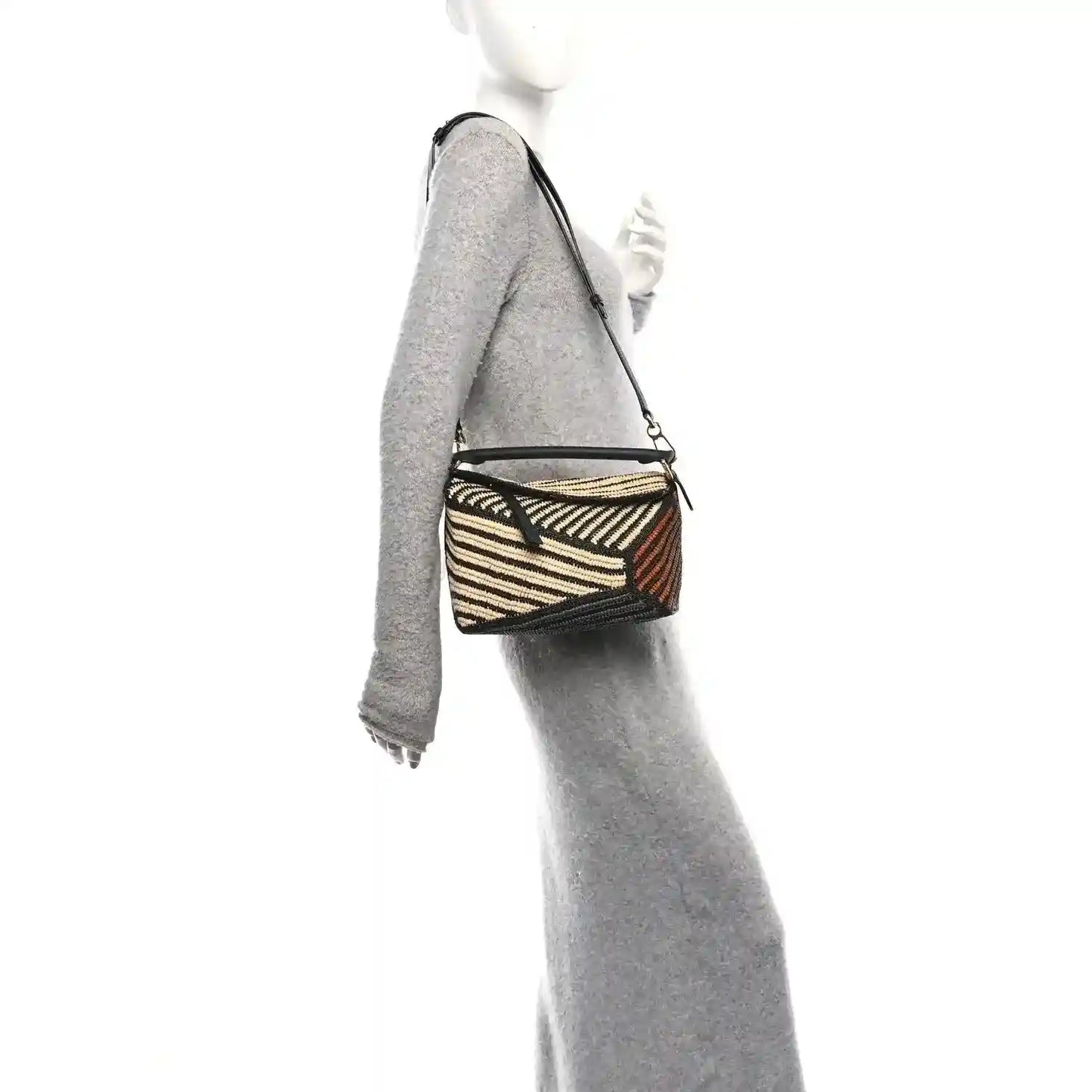 Small raffia puzzle bag worn crossbody with black leather strap and striped weave