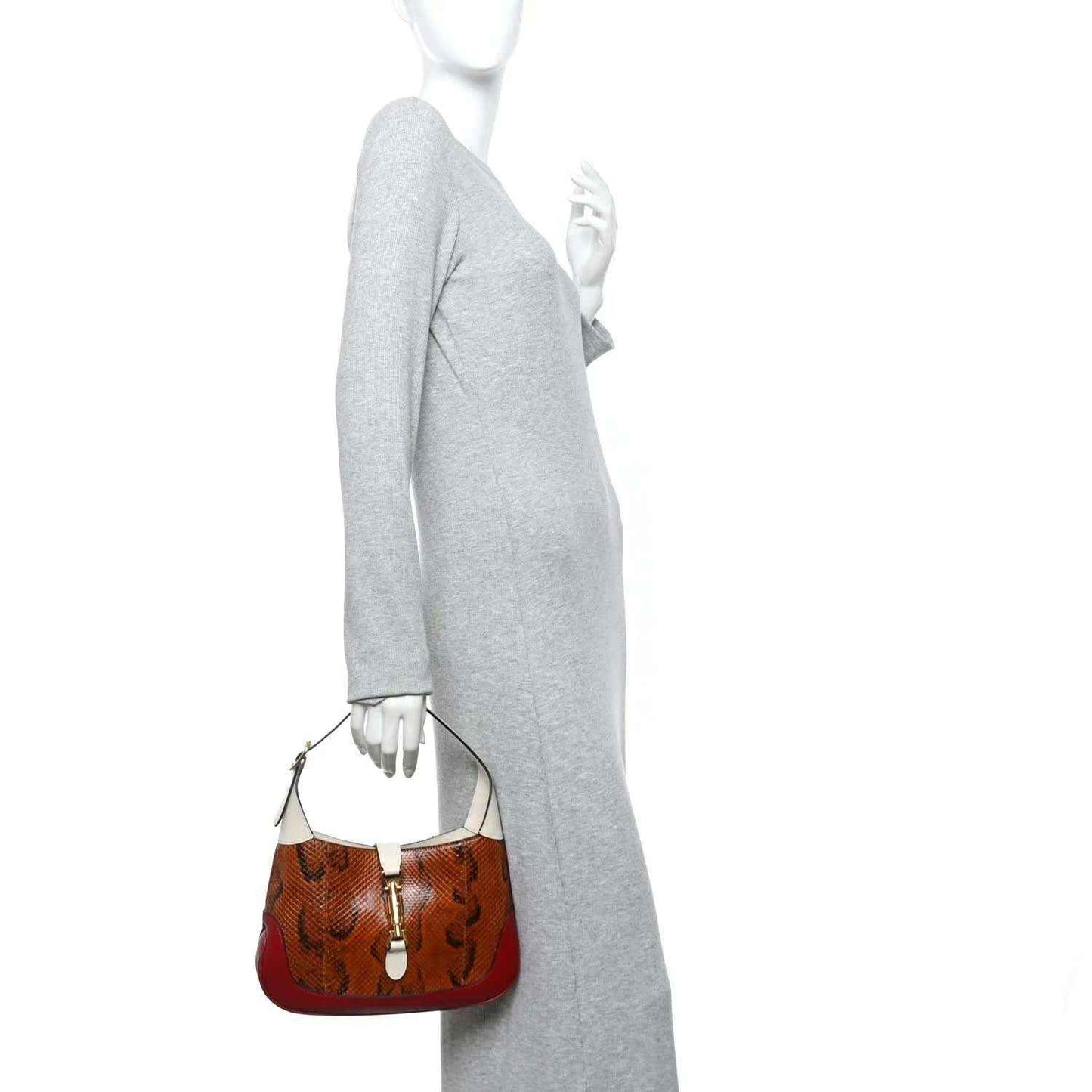 Small hobo bag held at side, brown snakeskin and burgundy base with cream strap.