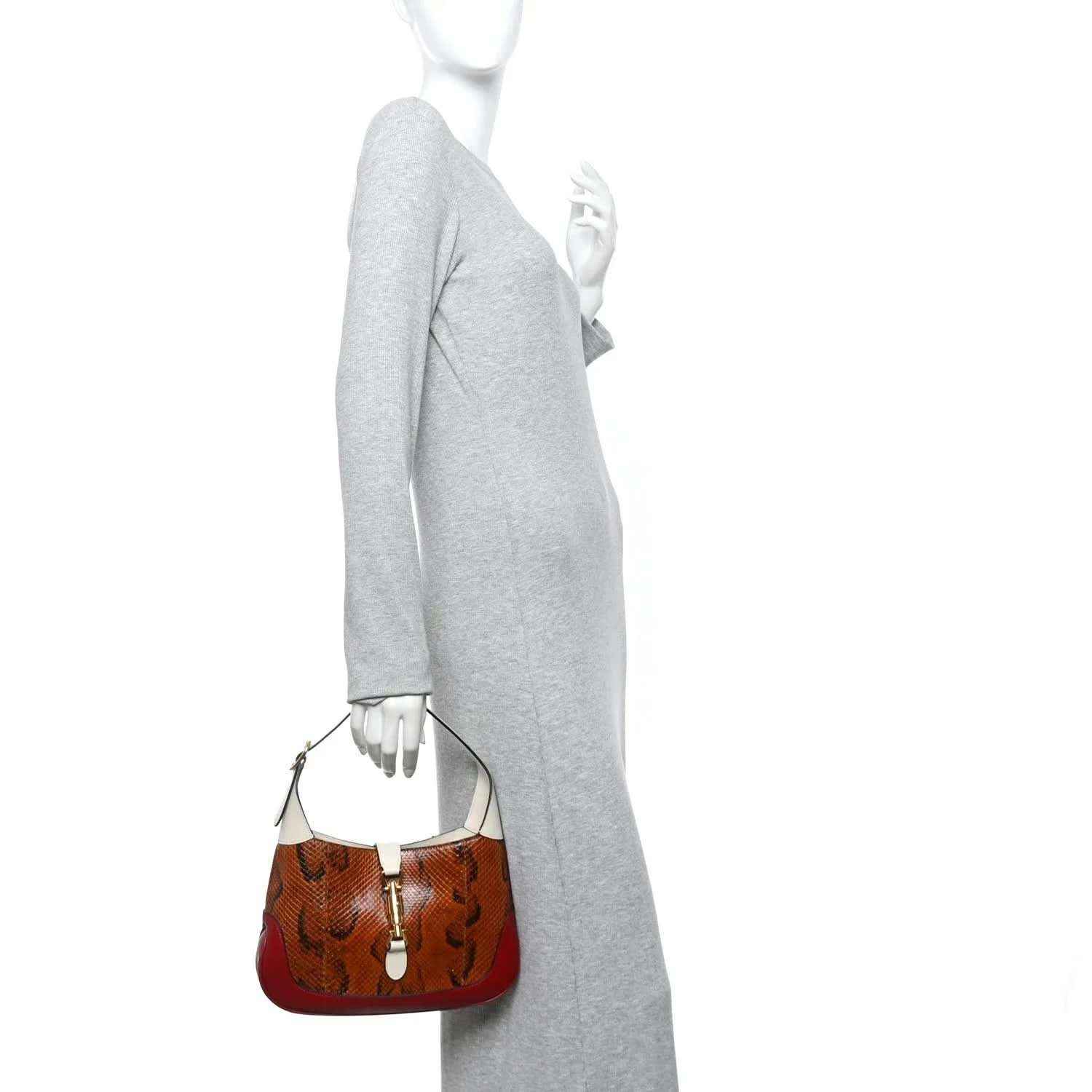 Small hobo bag held at side, brown snakeskin and burgundy base with cream strap.