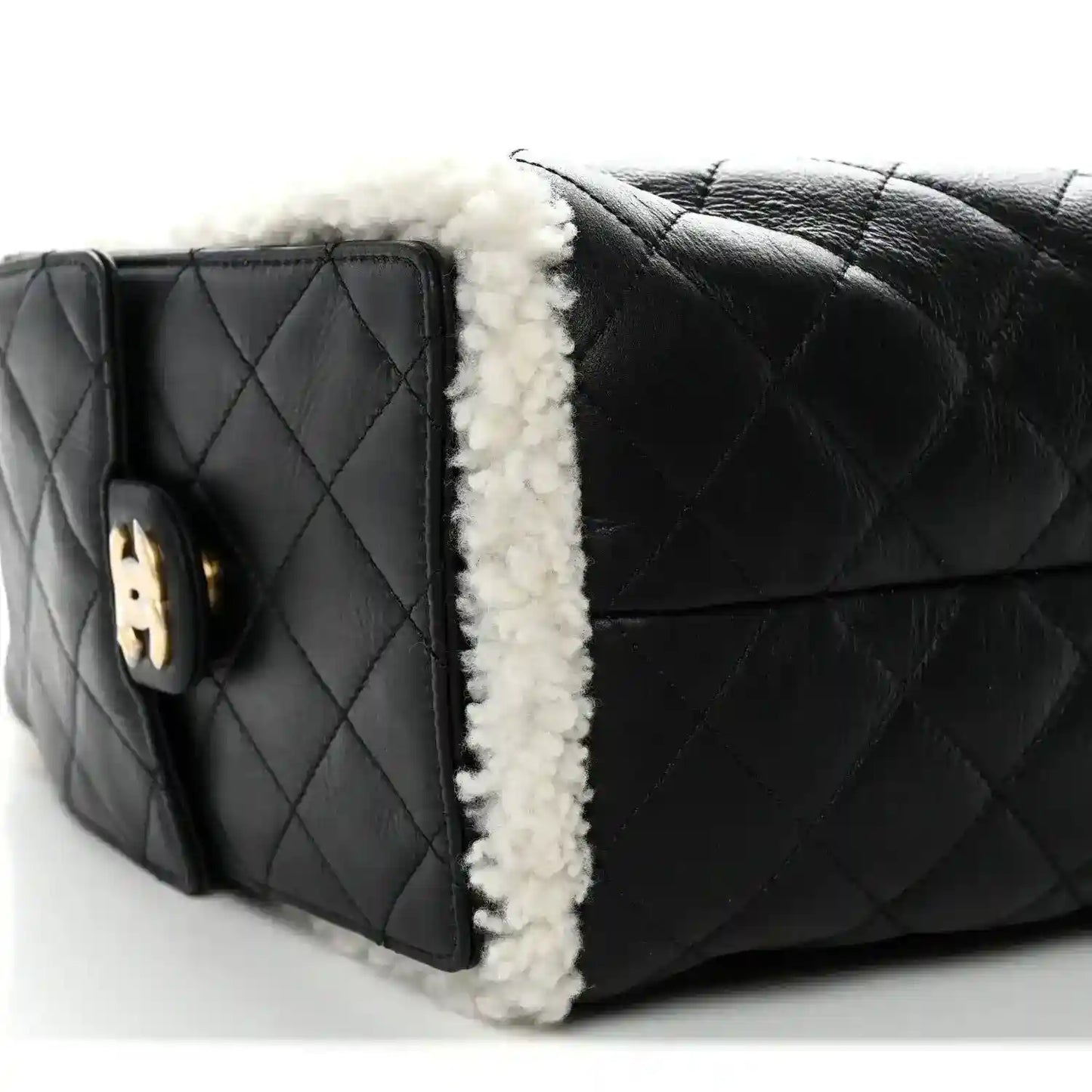 Black quilted handbag with white shearling edge trim and side emblem tab