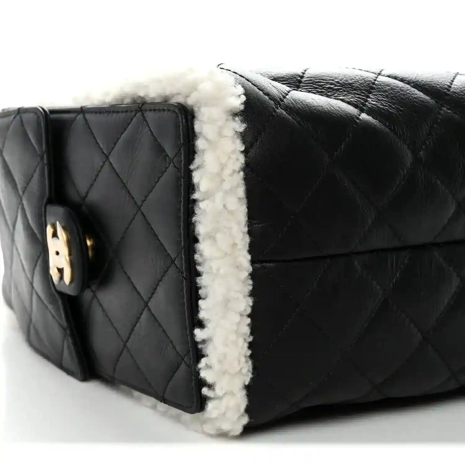 Black quilted handbag with white shearling edge trim and side emblem tab