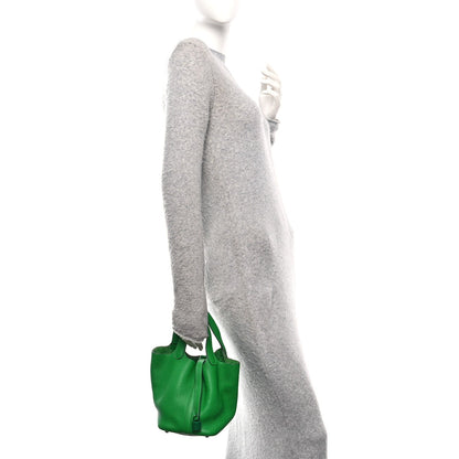 Picotin Lock 18 PM tote bag in green leather, carried by model with handles up