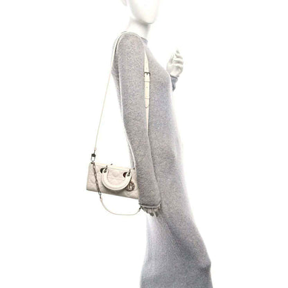 Small white quilted handbag on chain with short top handles and front charm