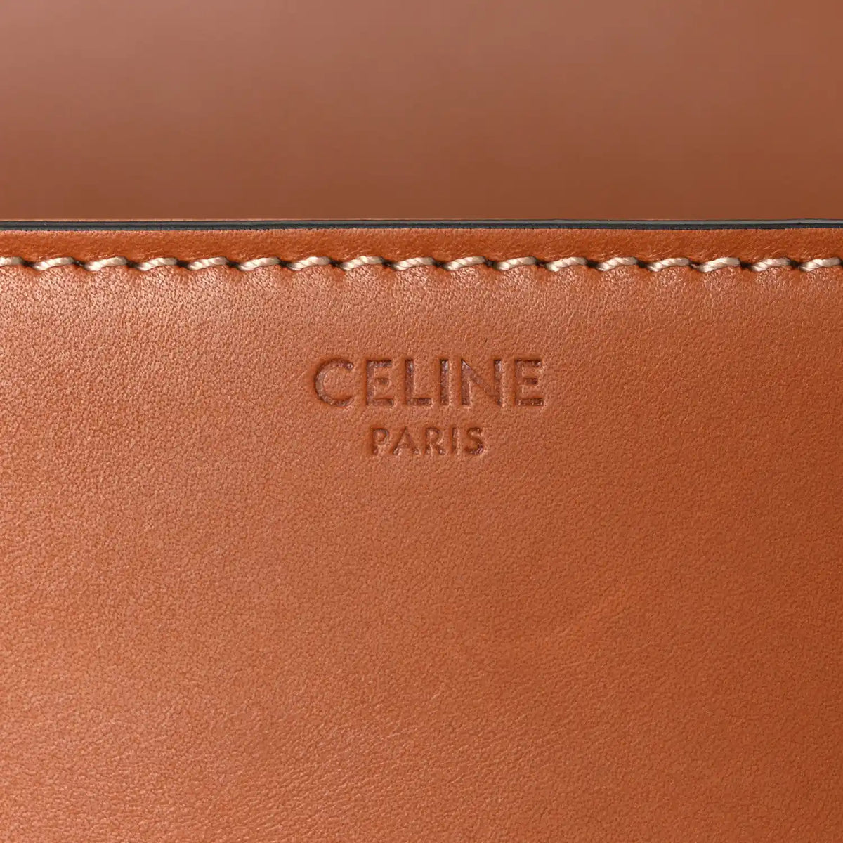 Celine embossed mark on tan leather panel with decorative stitched trim.