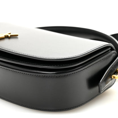Bicolor crossbody bag detail with white top, black body, and strap attachment.