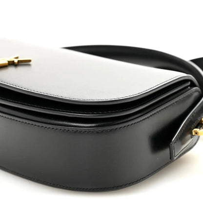 Bicolor crossbody bag detail with white top, black body, and strap attachment.